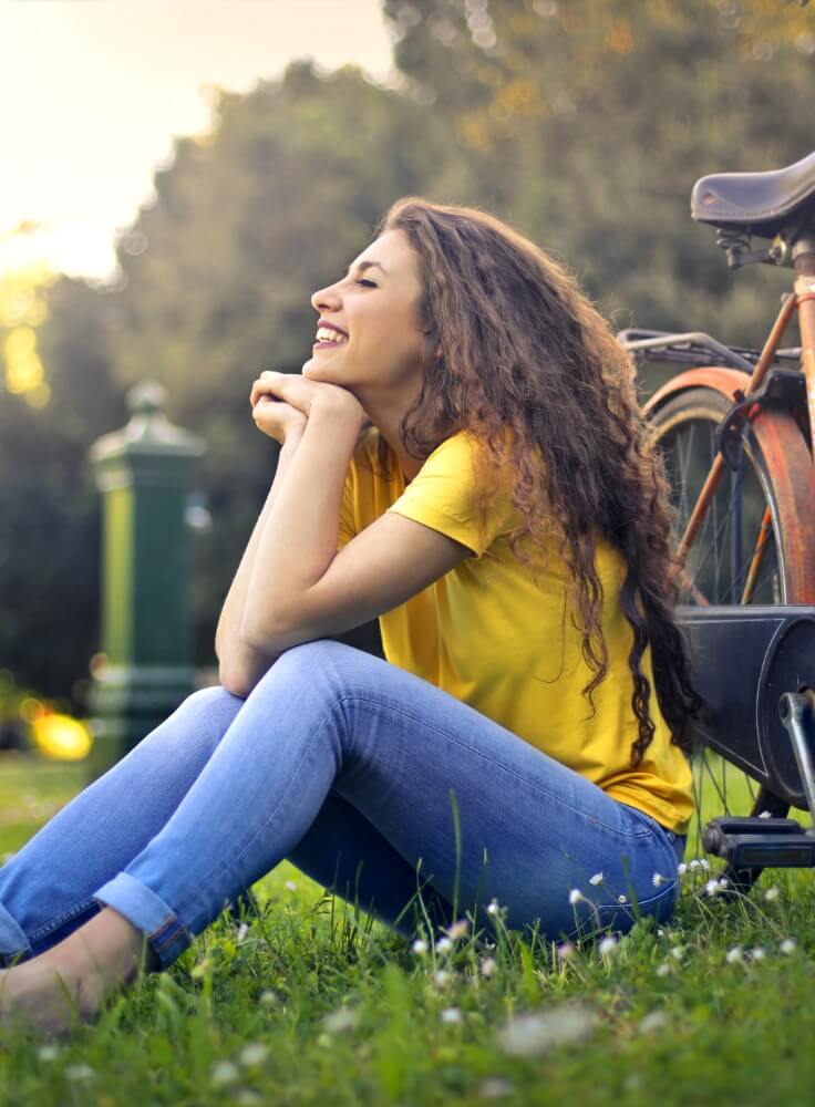 Neighborhood Living at The Townline Apartments Woman sitting on the grass beside a bicycle, representing the neighborhood lifestyle near The Townline Apartments.